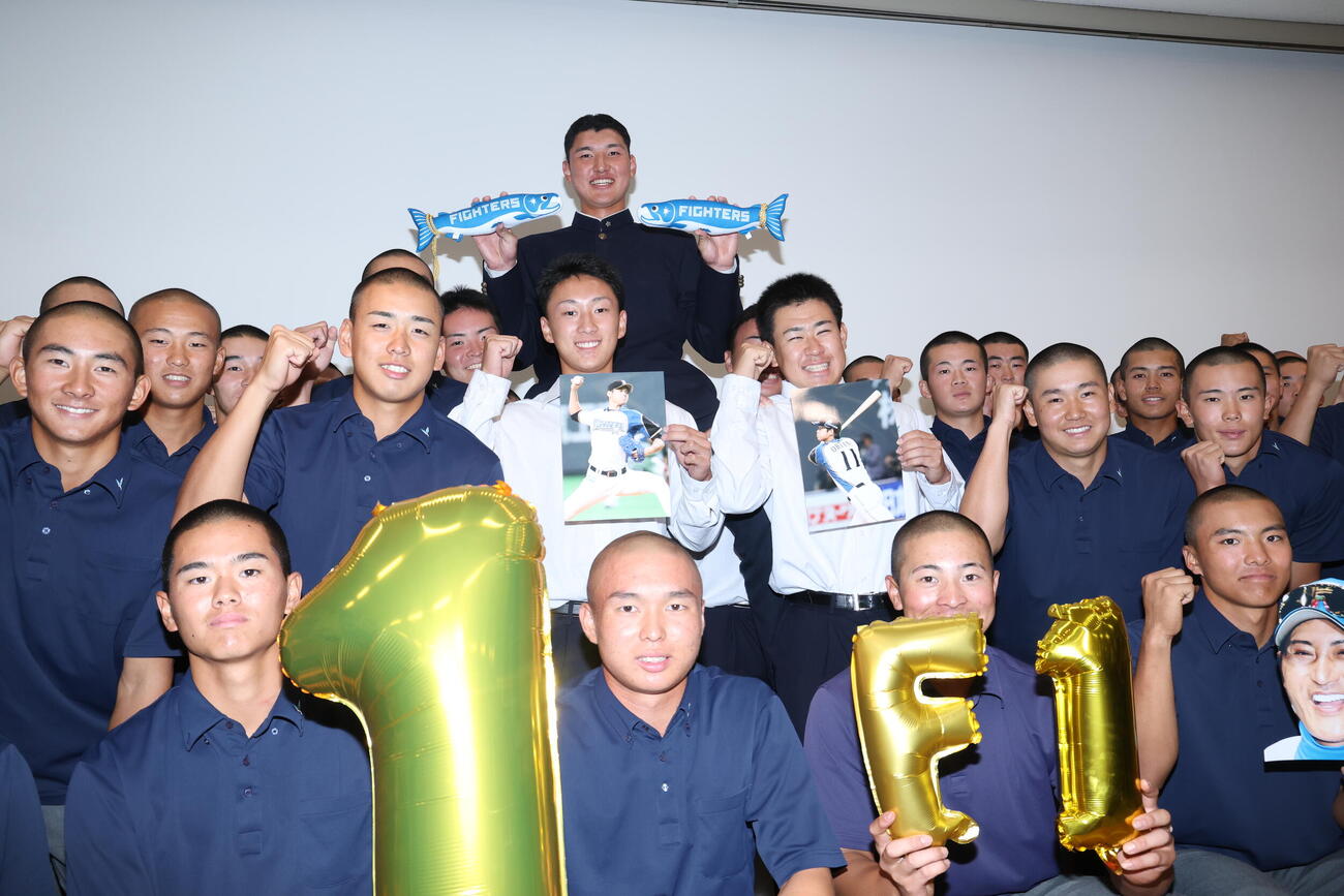 チームメートから騎馬の祝福を受けながら写真に納まる日本ハムから1位指名を受けた山梨学院・菰田陽生（中央上）（撮影・河田真司）