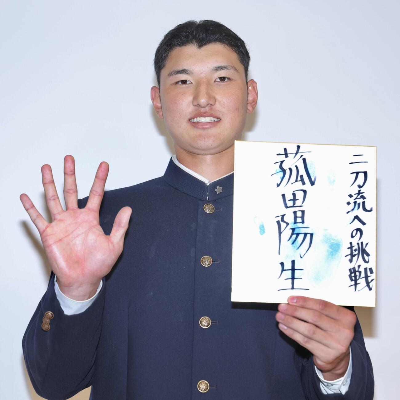 色紙を手に写真に納まる日本ハムから1位指名を受けた山梨学院・菰田陽生（撮影・河田真司）