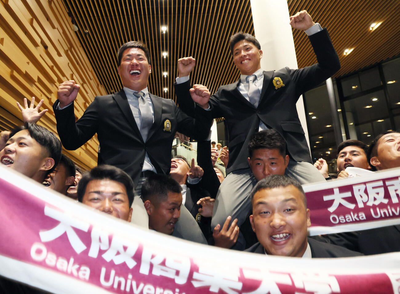 DeNAからドラフト1位指名を受けた大商大・星野世那（右）とオリックスからドラフト3位指名された春山陽登は、ナインに担がれ笑顔を見せる（撮影・宮崎幸一）