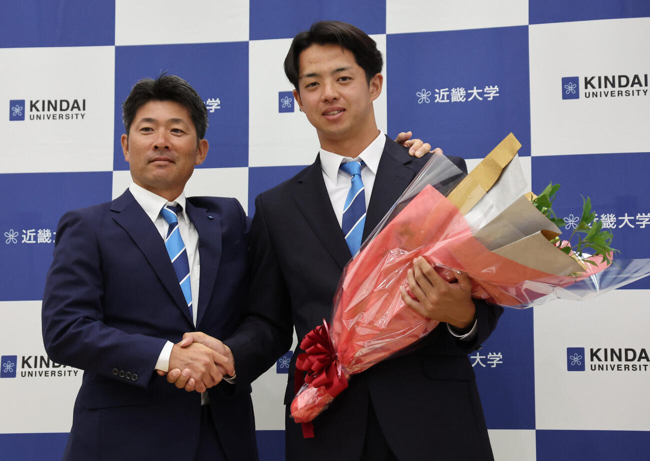 中日から1位で指名された近大・宮原廉（右）は松丸文政監督と握手をかわす（撮影・西尾就之）