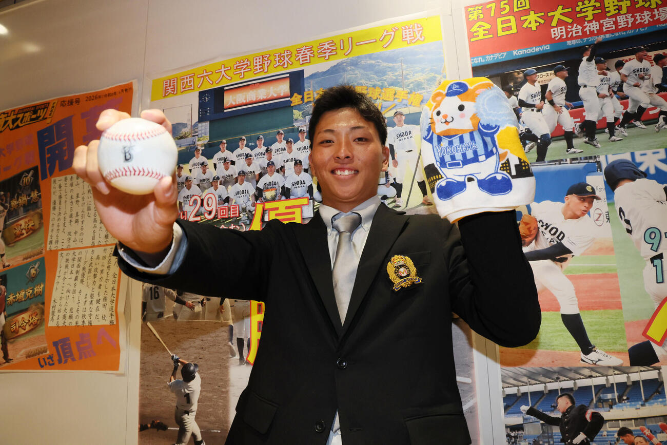 DeNAからドラフト1位指名を受けた大商大・星野世那はDeNAのボールと球団グッズを手に笑顔を見せる（撮影・宮崎幸一）