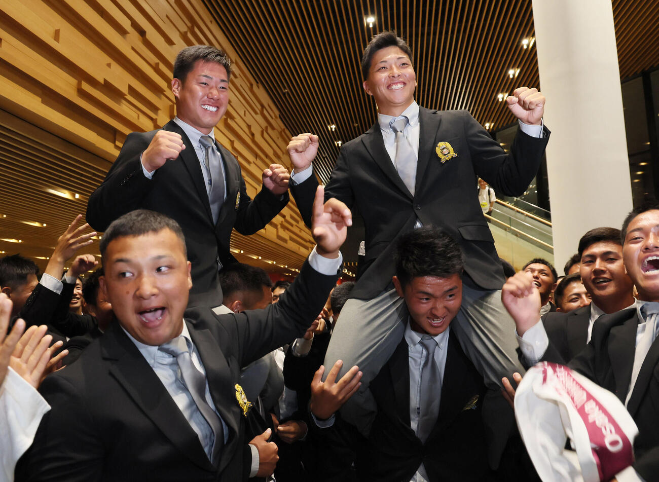 DeNAからドラフト1位指名を受けた大商大・星野世那（右）とオリックスからドラフト3位指名された春山陽登は、ナインに担がれ笑顔を見せる（撮影・宮崎幸一）