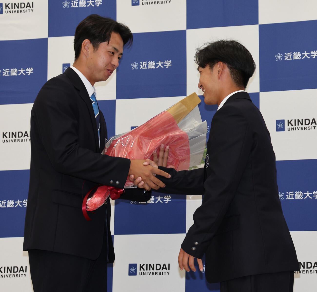 中日に1位で指名された近大・宮原廉（左）は八幡大介主将から花束を受け取る（撮影・西尾就之）
