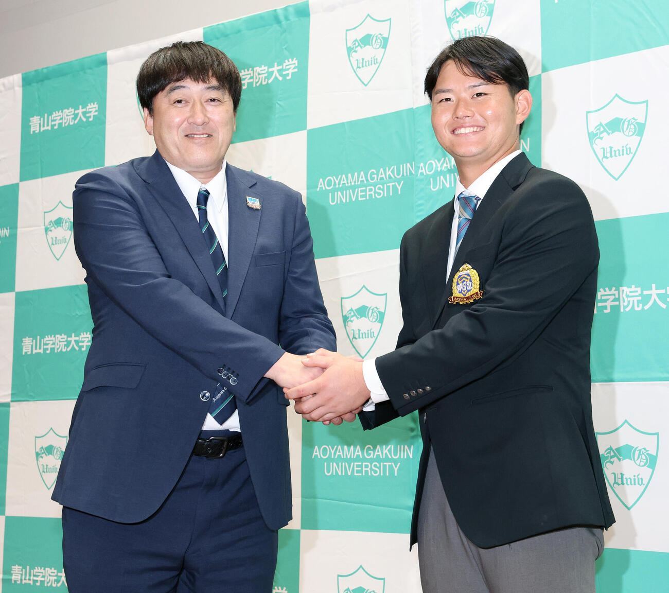 楽天石井一久GM（左）と笑顔で握手を交わすドラフト1位青学大・渡部海（撮影・宮地輝）