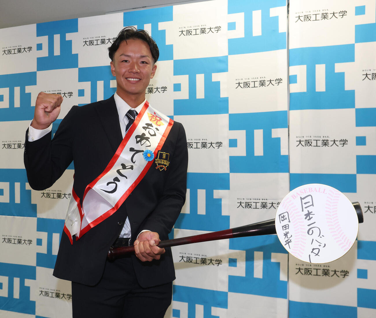 日本一のバッターと目標に書いた色紙とガッツポーズする日本ハムから育成1位の指名を受けた大工大・岡田光平（撮影・白石智彦）