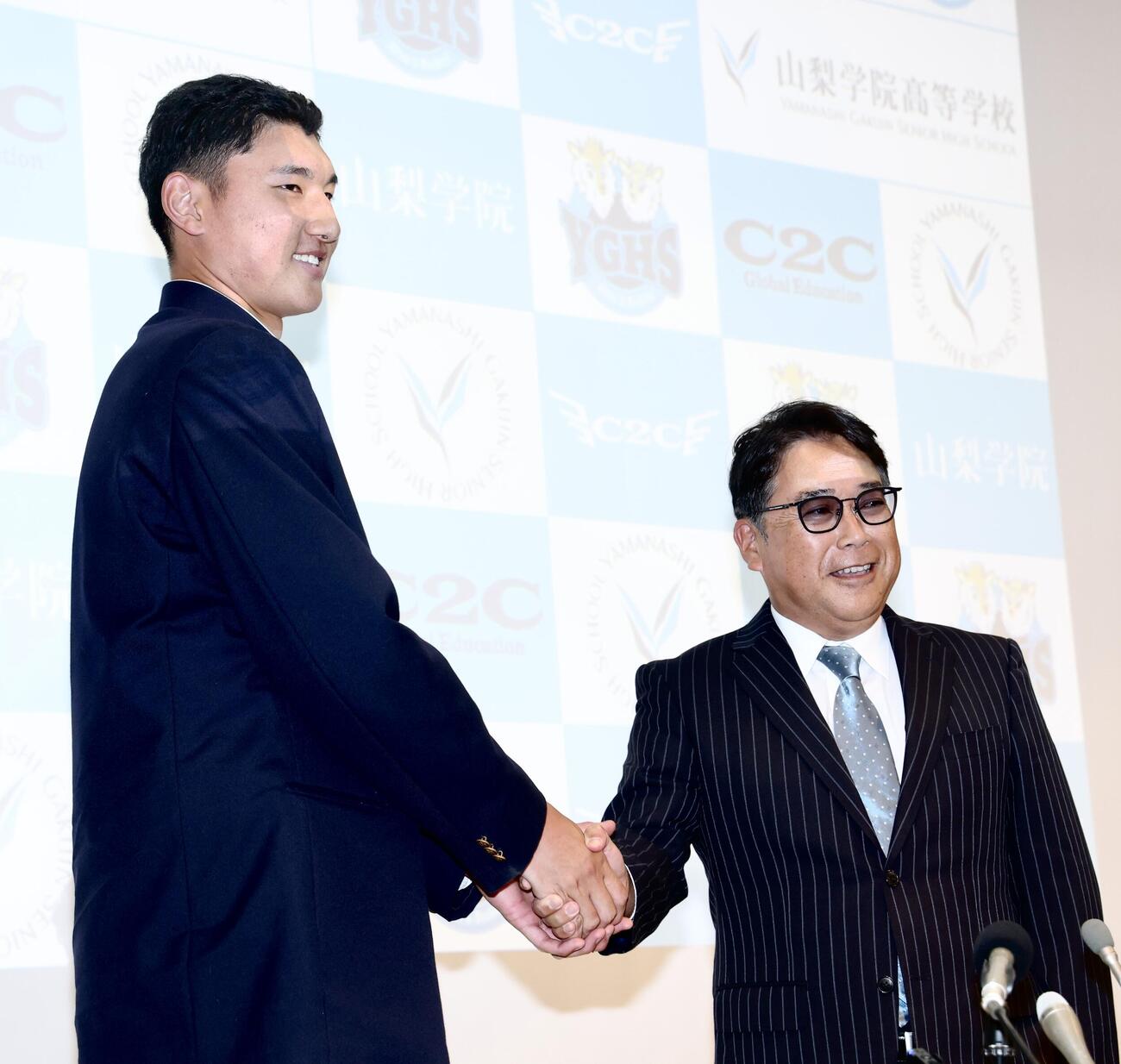 日本ハムから1位指名を受けた山梨学院・菰田陽生（左）は吉田洸二監督と握手を交わす（撮影・河田真司）