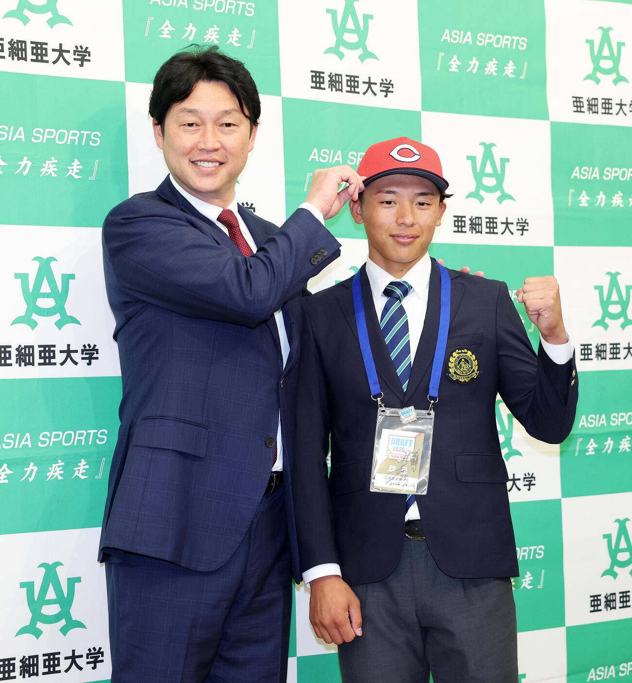 写真に納まる広島新井貴浩監督（左）とドラフト1位の亜大・山里宝（撮影・鈴木正人）