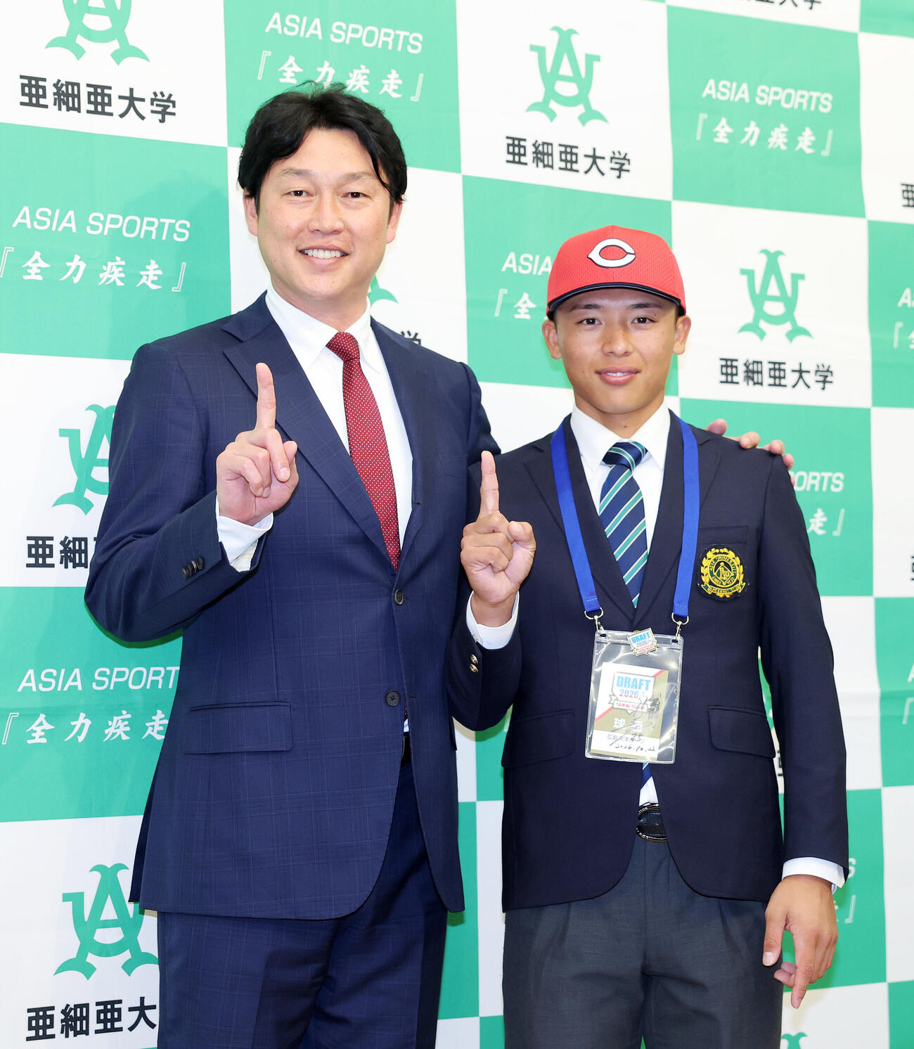 写真に納まる広島新井貴浩監督（左）とドラフト1位の亜大・山里宝（撮影・鈴木正人）
