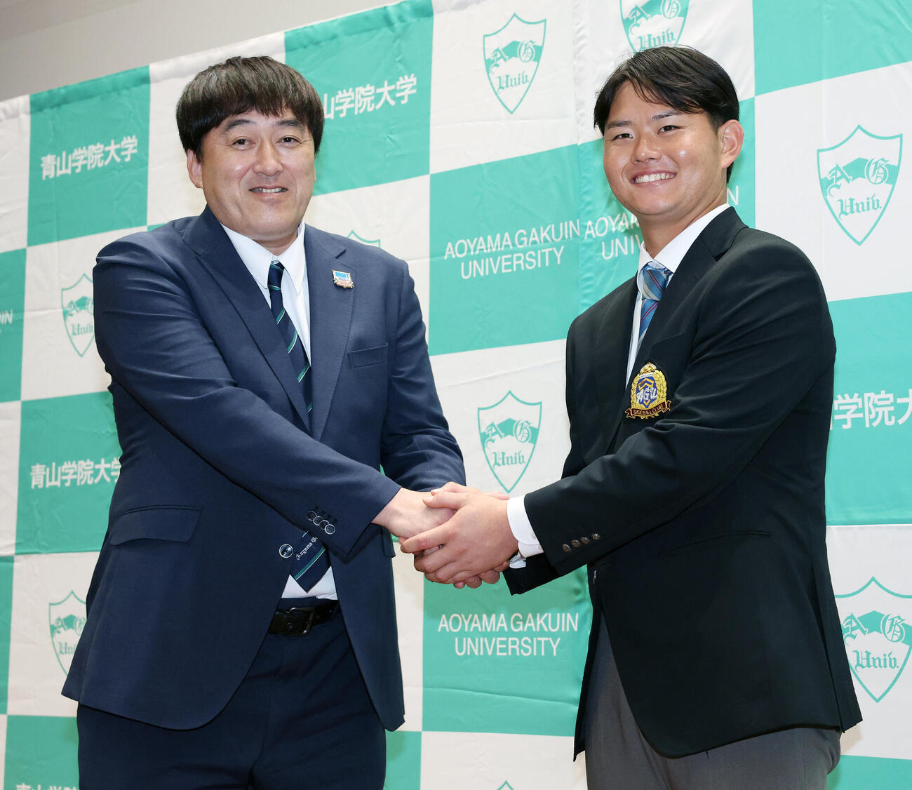 楽天石井一久GM（左）と笑顔で握手を交わすドラフト1位青学大・渡部海（撮影・宮地輝）