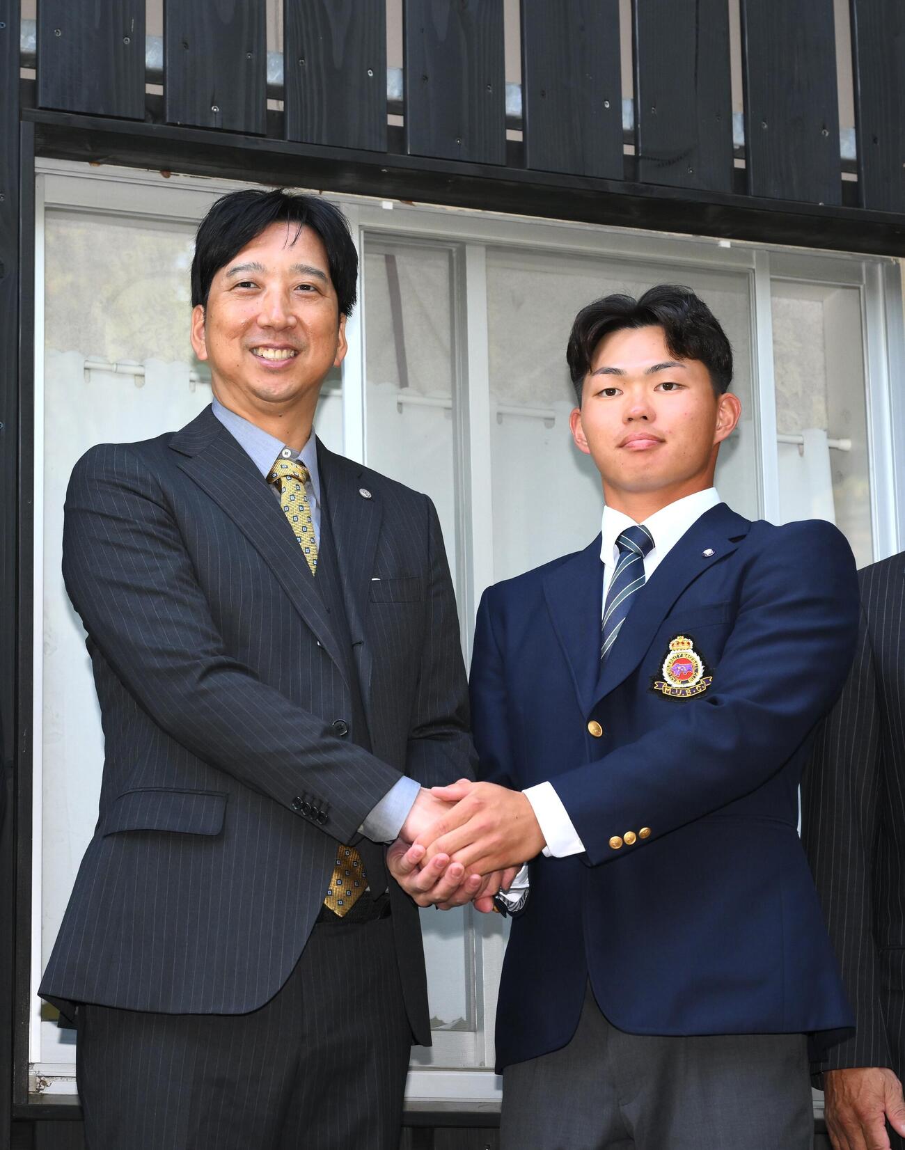 指名あいさつに訪れた阪神藤川球児監督（左）と握手を交わすドラフト1位の明大・榊原七斗（撮影・滝沢徹郎）