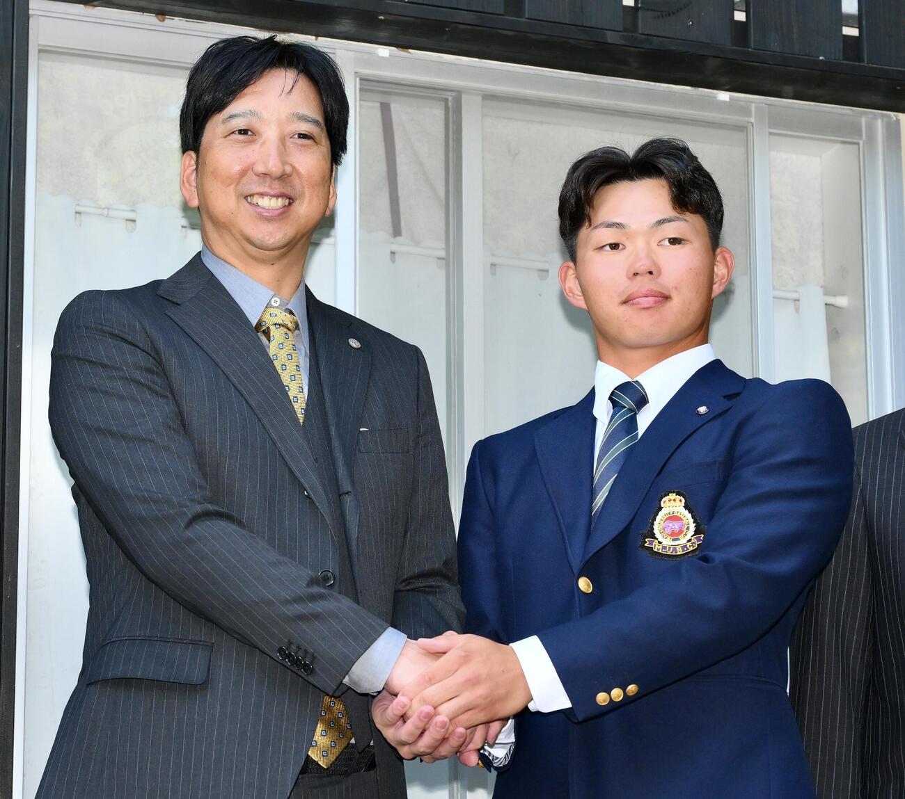 指名あいさつに訪れた阪神藤川球児監督（左）と握手を交わすドラフト1位の明大・榊原七斗（撮影・滝沢徹郎）