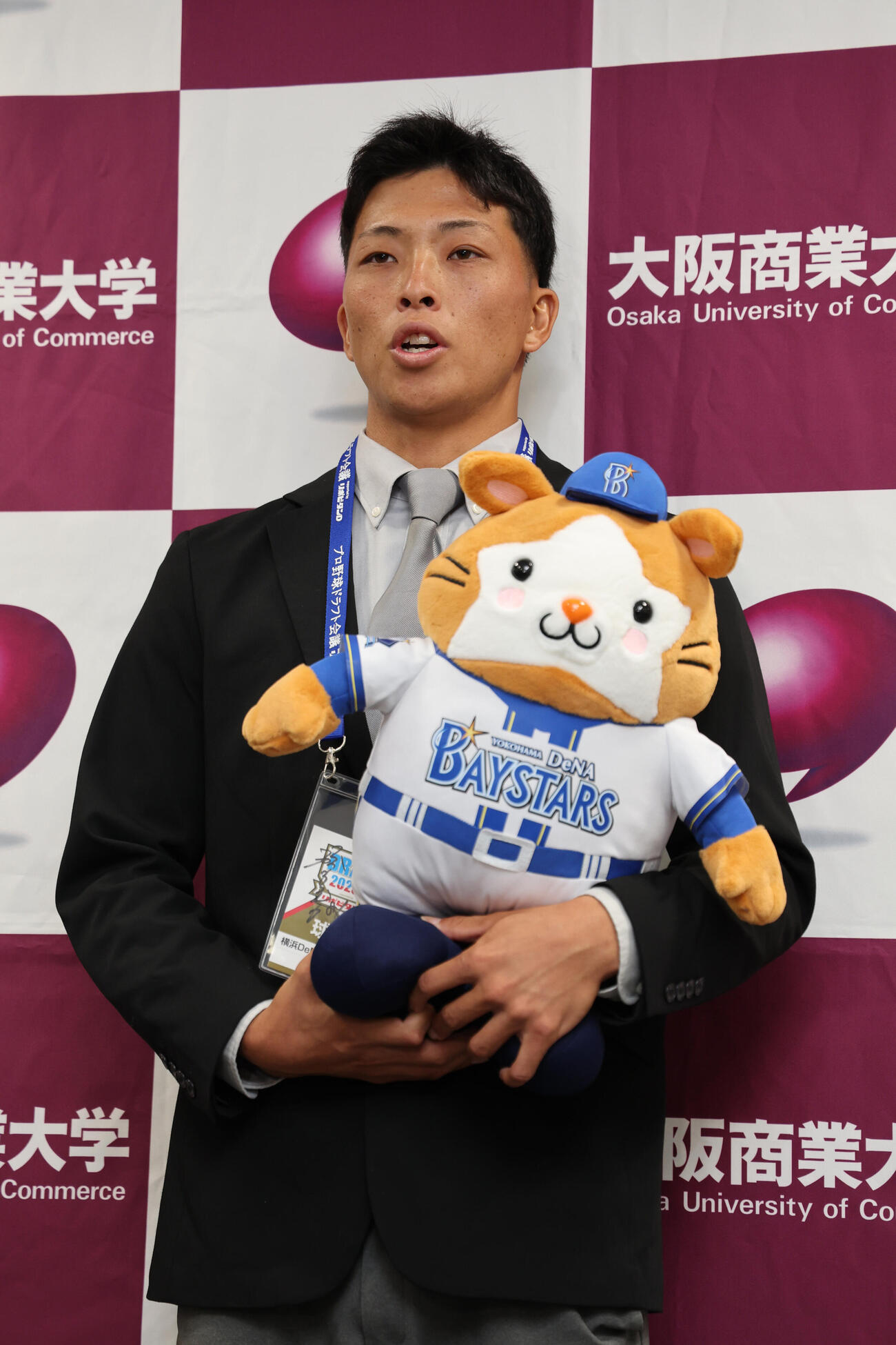 DeNA1位の大商大・星野世那は相川亮二監督のサイン入りパスとマスコットを手にポーズをとる（撮影・西尾就之）