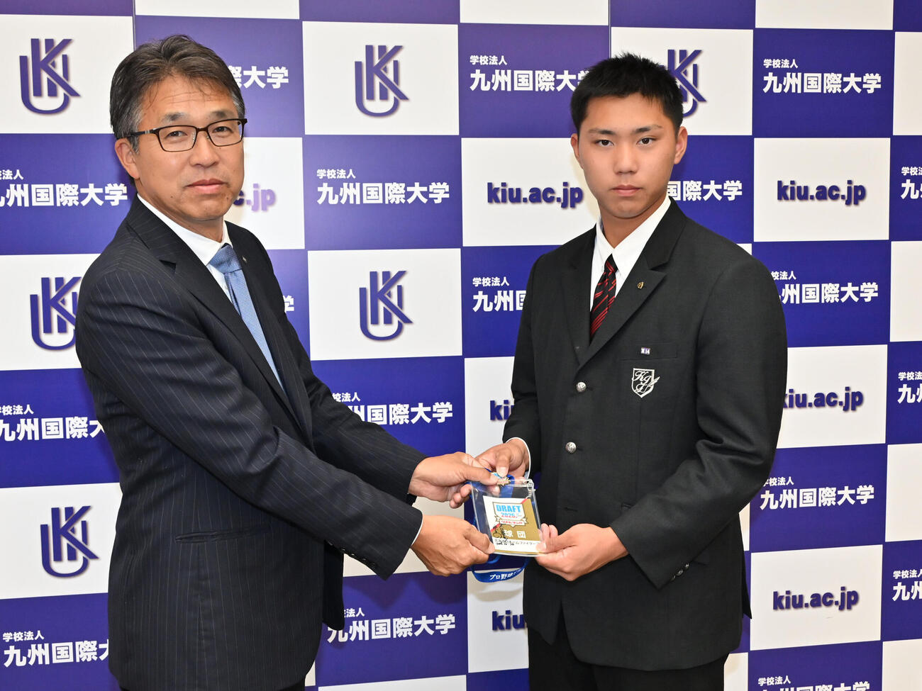 ドラフト会議時のIDを九州国際大付・牟礼翔（右）にプレゼントする日本ハム大渕隆スカウト部長（撮影・林敢治）