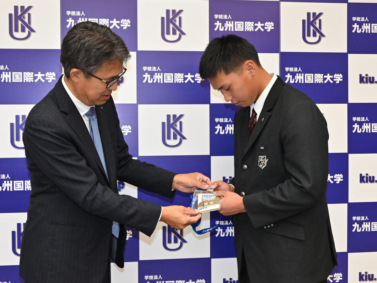ドラフト会議時のIDを九州国際大付・牟礼翔（右）にプレゼントする日本ハム大渕スカウト部長（撮影・林敢治）