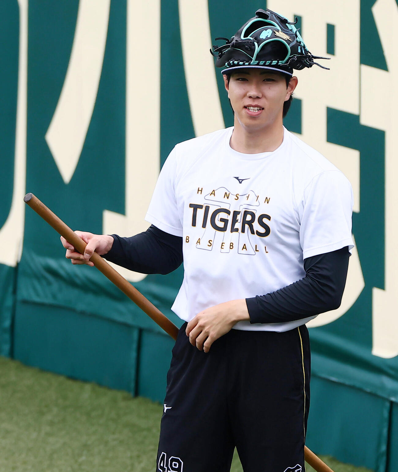 外野でグラブを頭に載せて長尺棒をあやつる阪神工藤泰成（撮影・加藤哉）