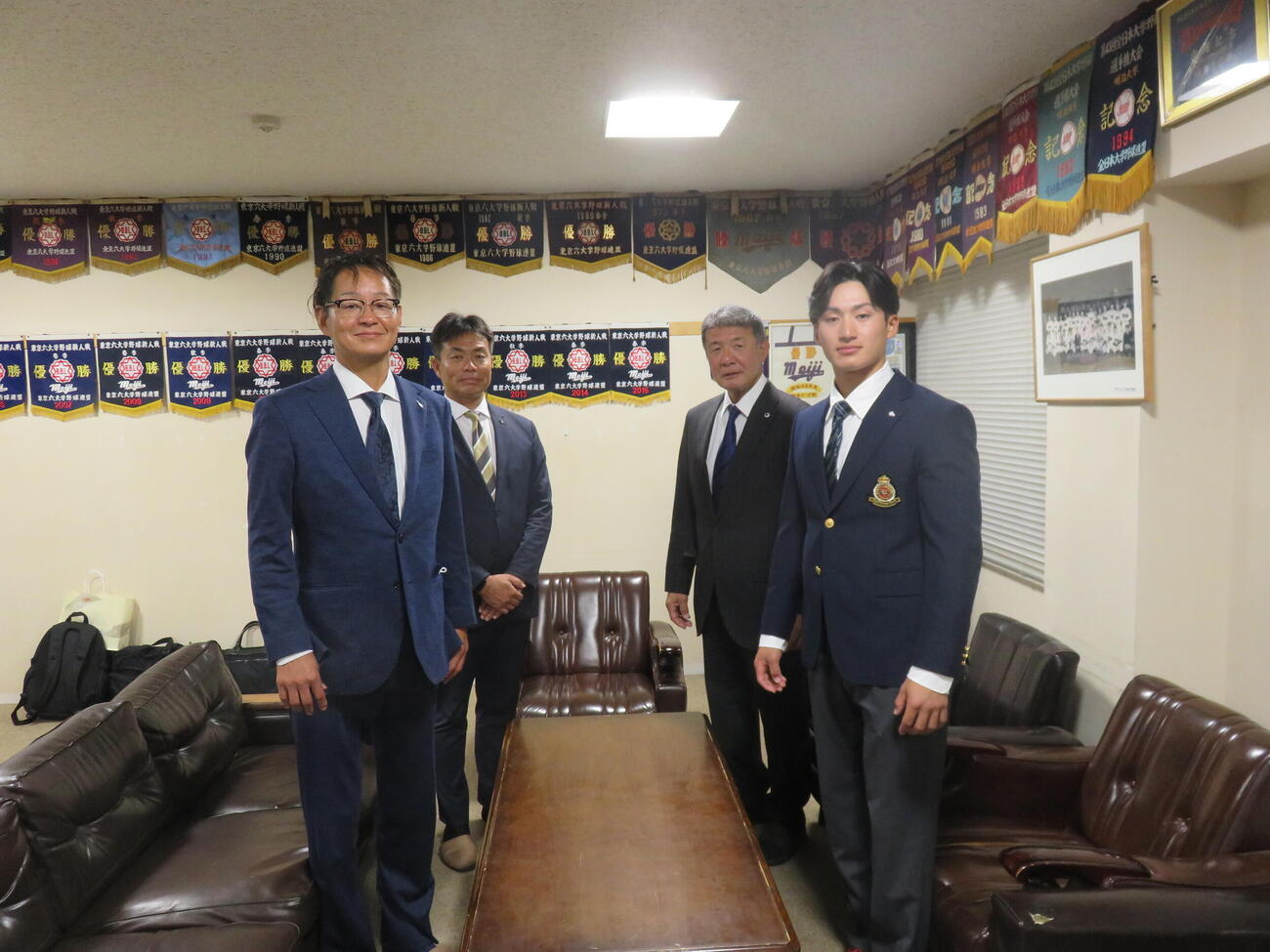 楽天部坂俊之スカウト（左）、愛敬尚史スカウト部長（左から2人目）から指名挨拶を受けた、ドラフト2位指名を受けた明大・岡田啓吾内野手（右）と明大・戸塚俊美監督。（撮影・斎藤直樹）