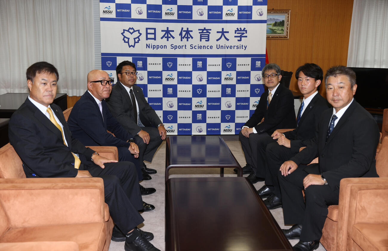指名あいさつに訪れた。左から阪神の平塚克洋スカウト、畑山俊二統括スカウト、東辰弥編成ディレクターと日体大野球部の大石健二部長、2位指名の馬場拓海、古城隆利監督は記念撮影に応じる（撮影・柴田隆二）