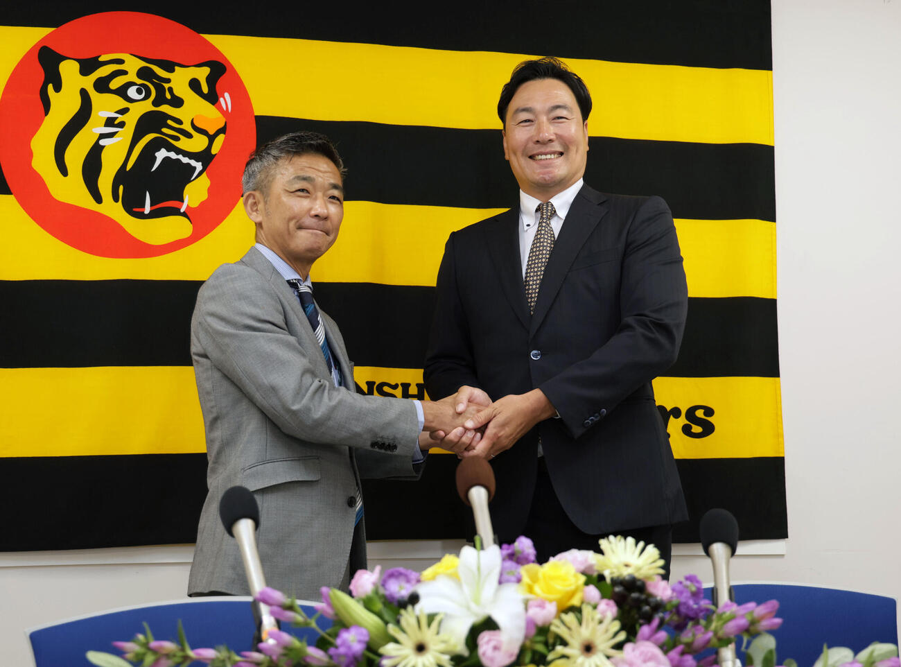 阪神の2軍投手コーチに就任した筒井和也スカウトは、竹内孝行球団副本部長と握手を交わす（撮影・宮崎幸一）
