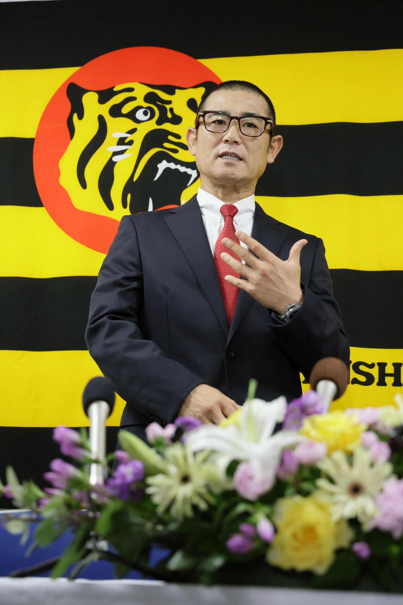 阪神の1軍打撃コーチに就任した坪井智哉氏は、虎のマークをバックに抱負を語る（撮影・宮崎幸一）