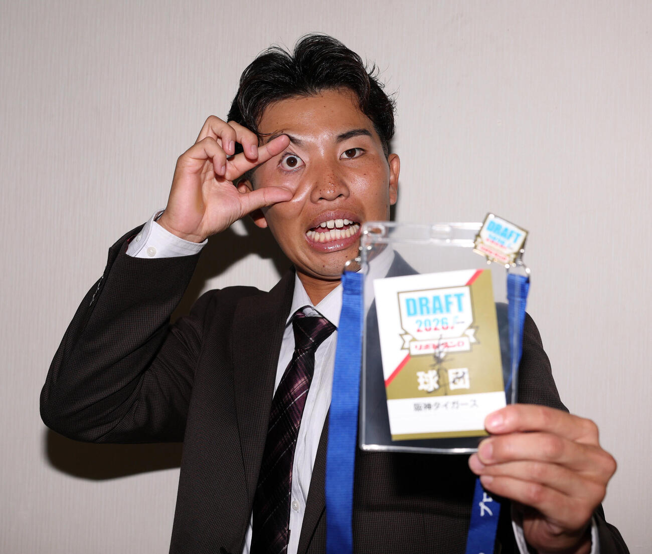 阪神指名あいさつを受けた東京ガスの越川海翔は、藤川球児監督サイン入りのドラフト会議IDを手に、プロレスラー内藤哲也のポーズを決める（撮影・浅見桂子）
