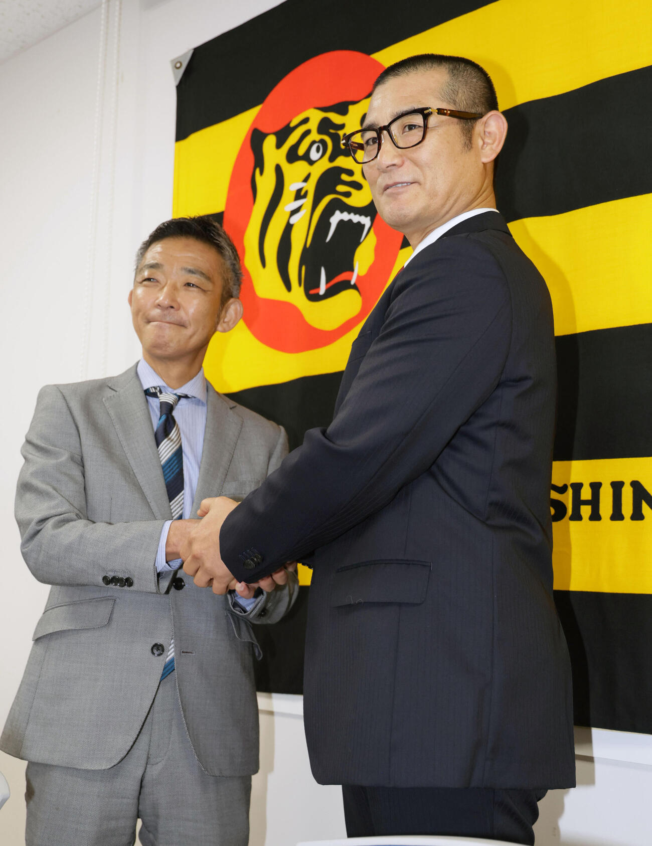 阪神の1軍打撃コーチに就任した坪井智哉氏は、竹内孝行球団副本部長（左）と握手を交わす（撮影・宮崎幸一）