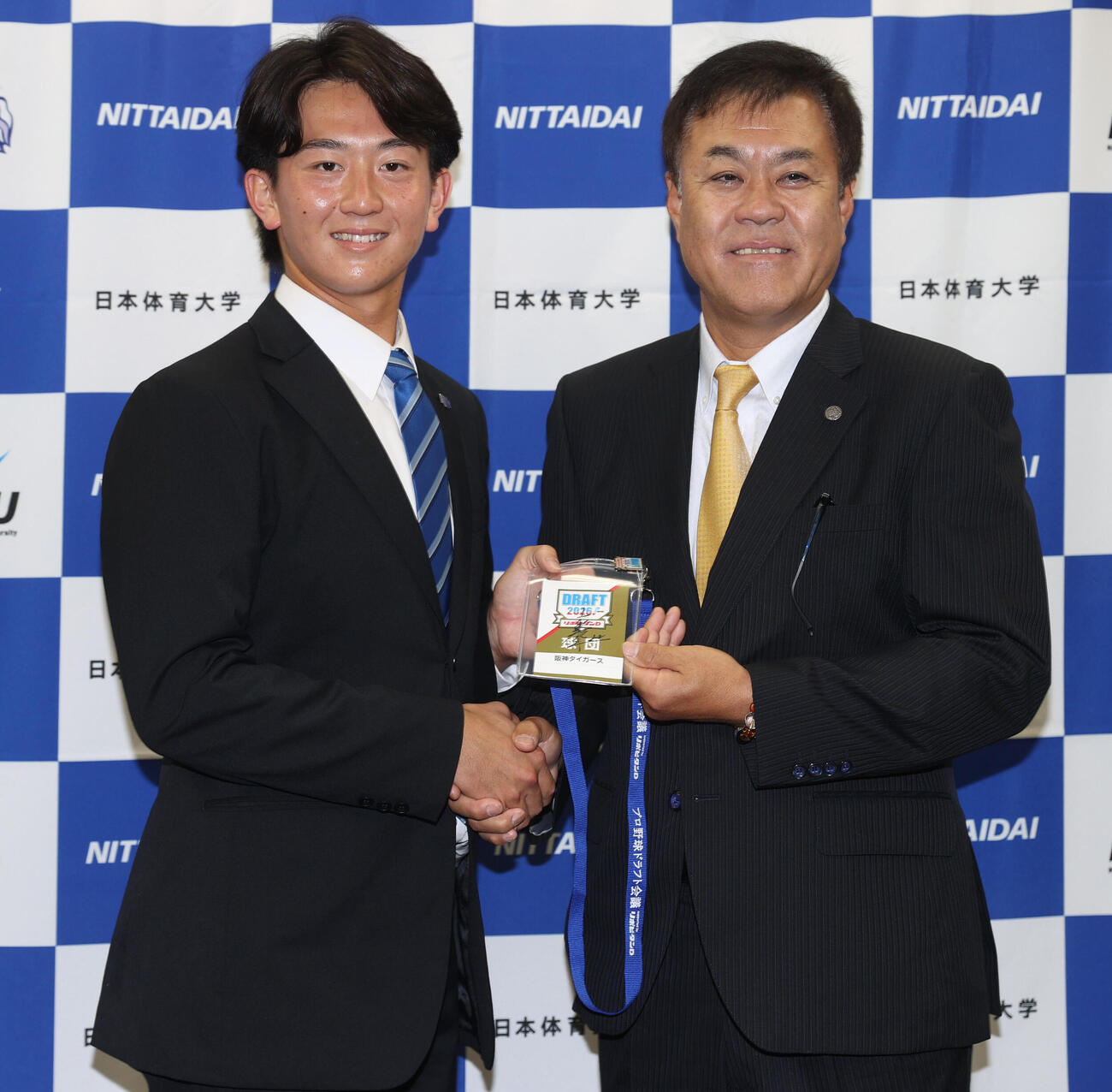 阪神2位指名の日体大・馬場拓海（左）は藤川球児監督のサイン入りドラフト会議入館証を平塚克洋スカウトから渡される（撮影・柴田隆二）