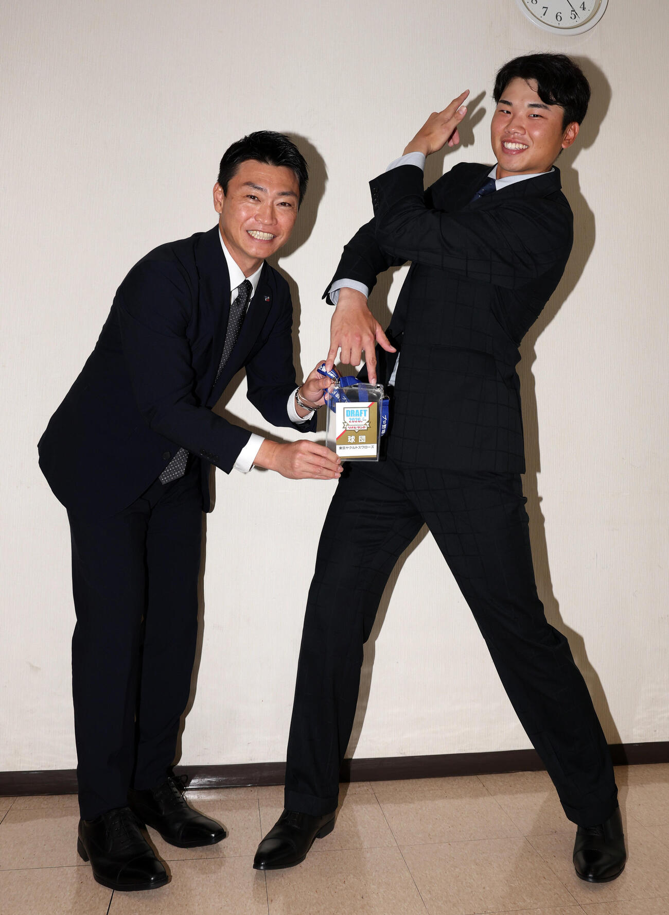 指名あいさつを受けた東京ガスの藤沢涼介（右）は、ジョジョ立ちして、ヤクルト青木宣親GMからドラフト会議IDを受け取る（撮影・浅見桂子）
