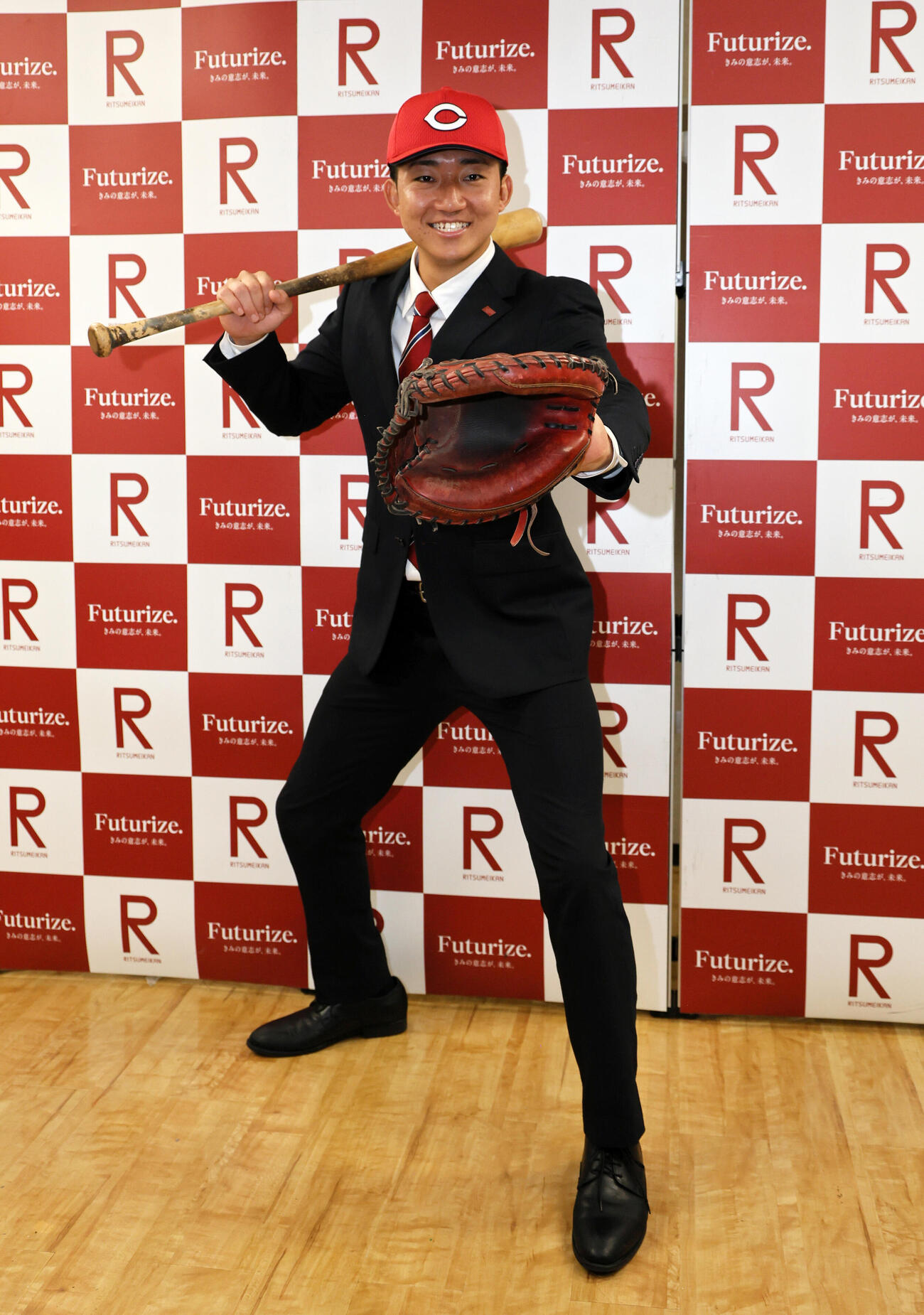 広島の指名挨拶を受けた立命大・西野啓也は、ミットとバットを手に笑顔を見せる（撮影・宮崎幸一）