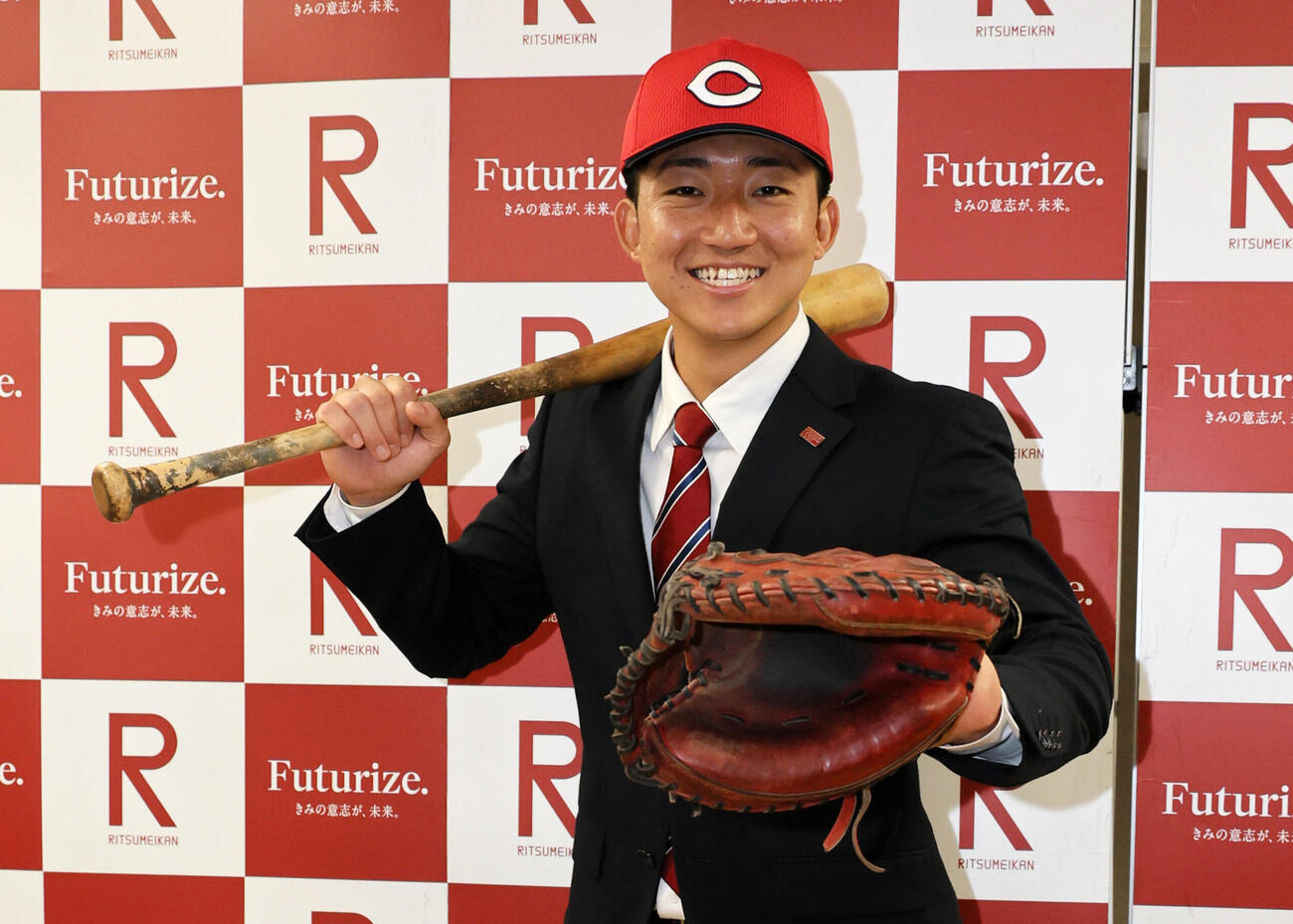 広島の指名挨拶を受けた立命大・西野啓也は、ミットとバットを手に笑顔を見せる（撮影・宮崎幸一）