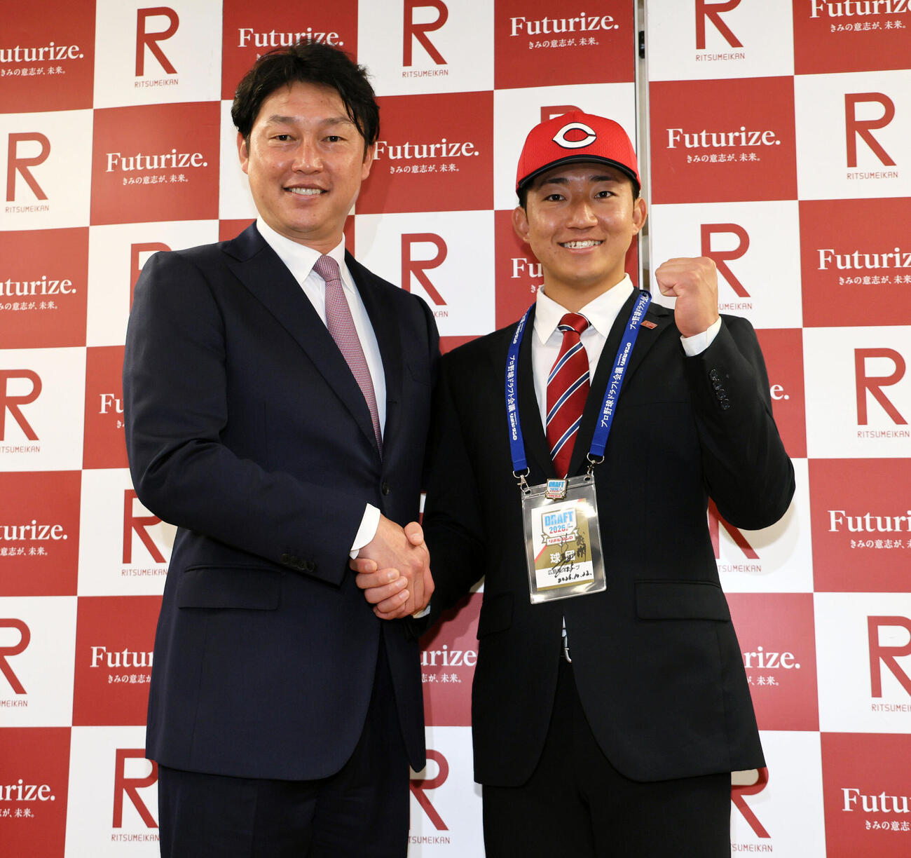 広島新井貴浩監督（左）の指名あいさつを受けた立命大・西野啓也は、広島の帽子をかぶり笑顔を見せる（撮影・宮崎幸一）