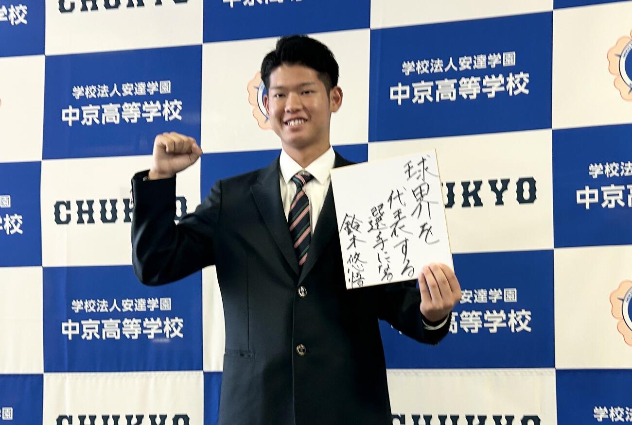 「球界を代表する選手になる」と記した色紙を手にガッツポーズを決める中日ドラフト4位の中京・鈴木悠悟内野手
