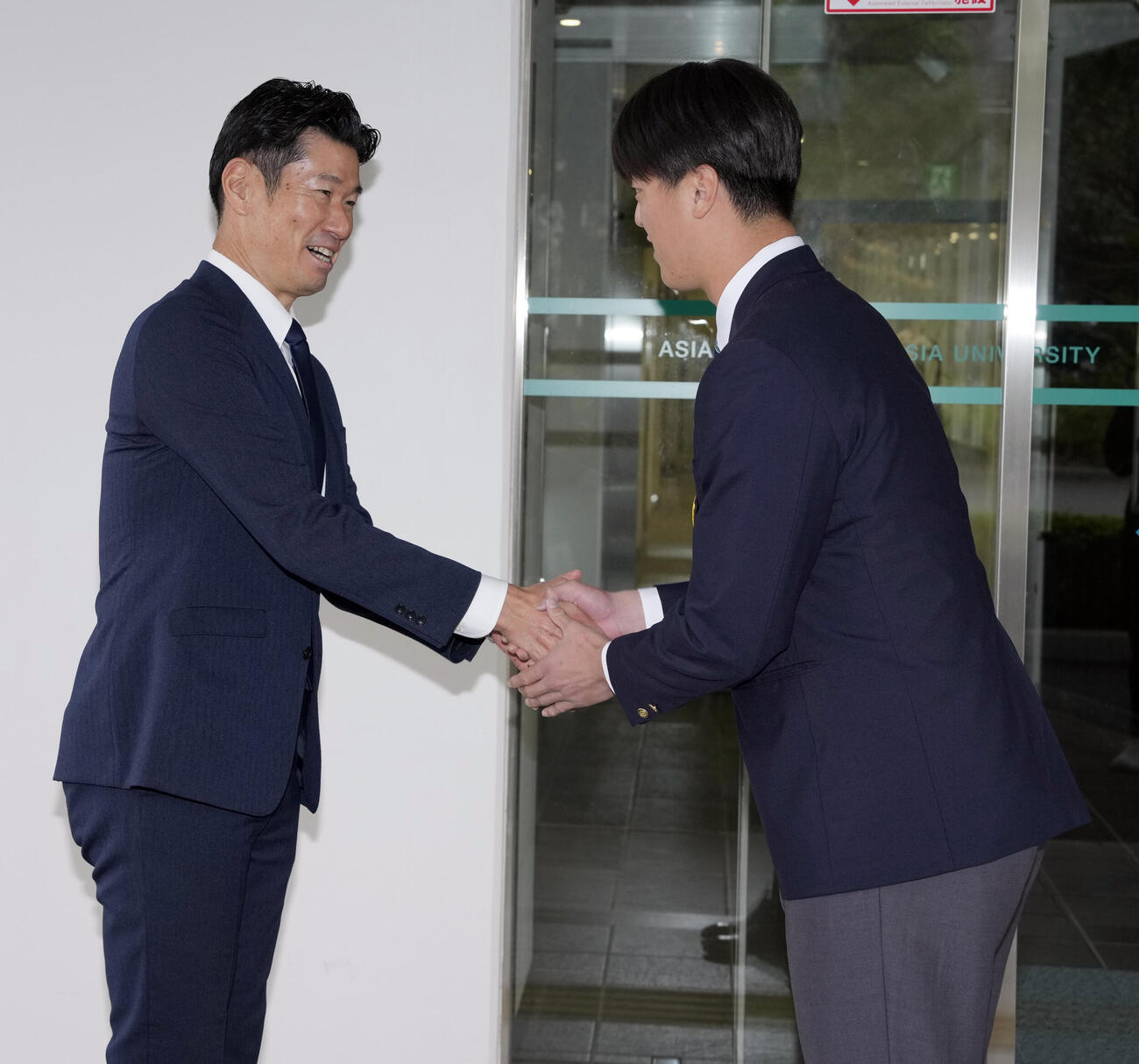握手を交わす西武広池浩司球団本部長（左）とドラフト1位の亜大・川尻啓人（撮影・小島史椰）