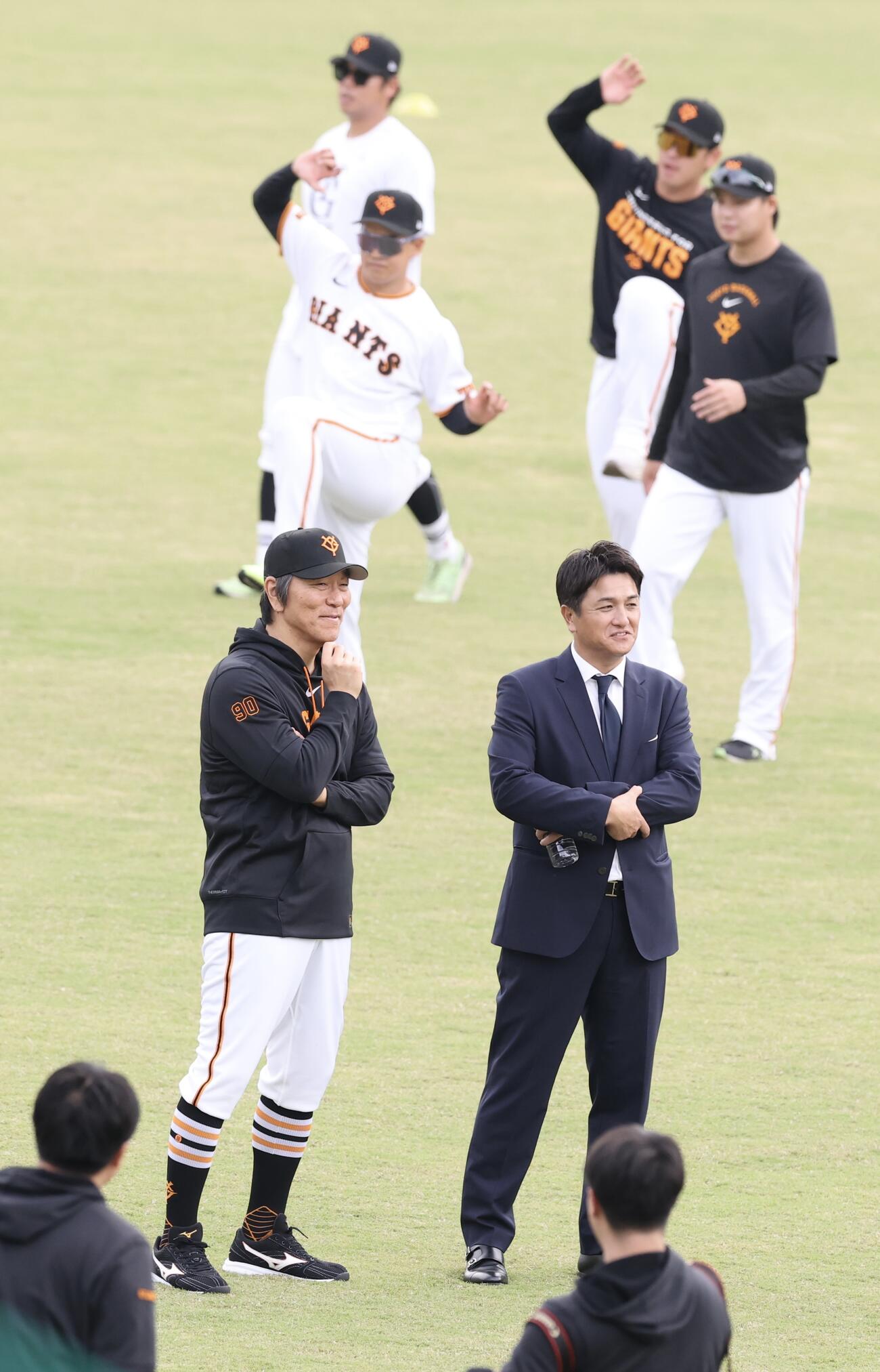 秋季キャンプ初日　練習する選手の中、話し込む巨人松井秀喜監督(左)と高橋由伸ヘッドコーチ(撮影・浅見桂子)