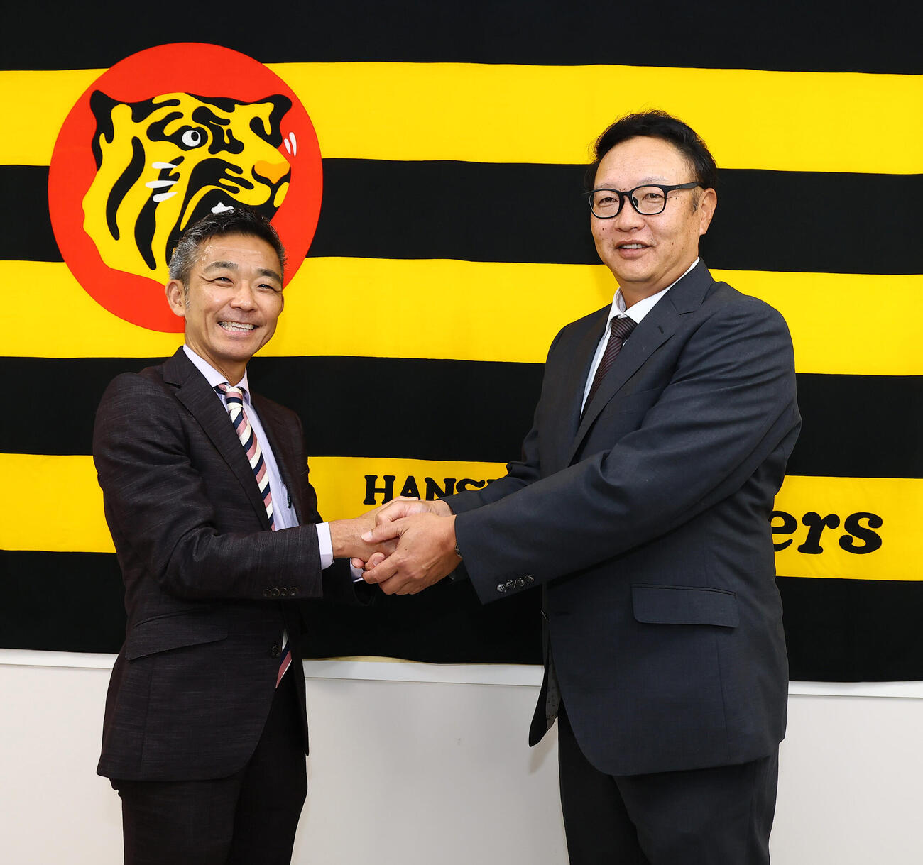 就任会見を行い竹内孝行球団副本部長（左）と握手する阪神福原忍投手巡回コーチ（撮影・加藤哉）