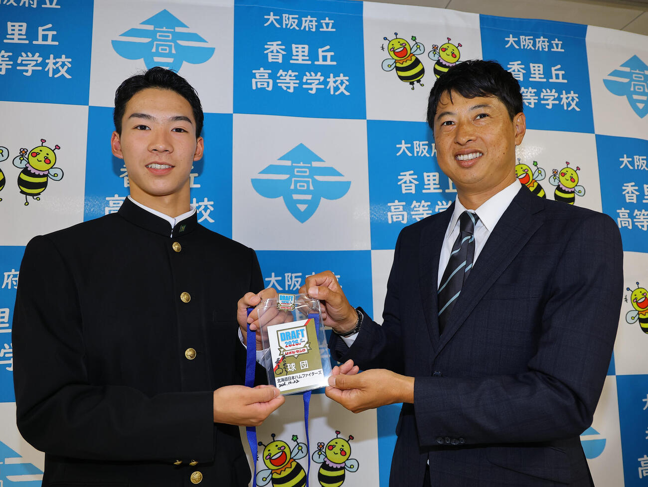 日本ハム・村田透スカウト（右）から栗山英樹CBOサイン入りのパスを手に笑顔を見せるドラフト5位指名の岡本翔斗（撮影・上田博志）