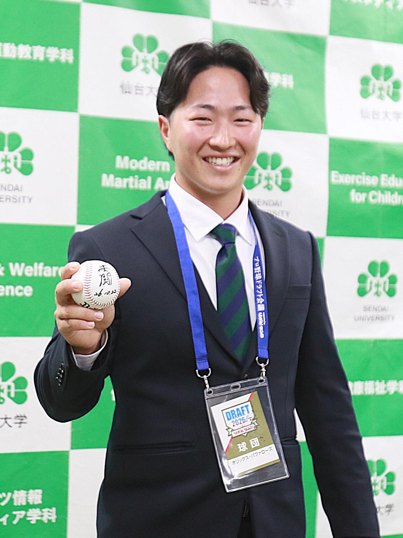 岸田監督のから「共闘」とメッセージが記されたサインボールを手に笑顔の仙台大・井尻琉斗捕手（撮影・高橋香奈）