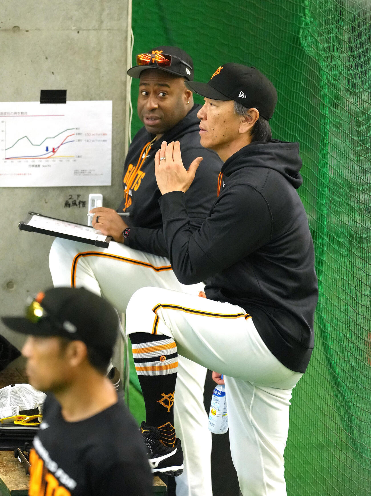 巨人松井秀喜監督（右）はゼラス・ウィーラー2軍打撃コーチと会話を交わしながら室内打撃練習を見つめる（撮影・足立雅史）