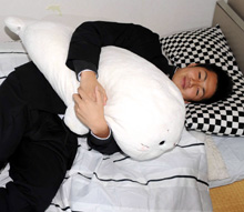 お気に入りの抱き枕をかかえベッドでリラックスするロッテ唐川（撮影・下田雄一）