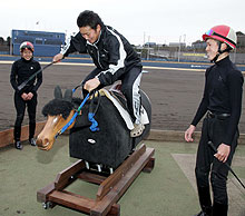 競馬学校生との交流会で練習用木馬に乗りムチを打つ中田（撮影・黒川智章）