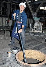 泡盛が入ったたるをかき混ぜる渡辺俊（撮影・為田聡史）