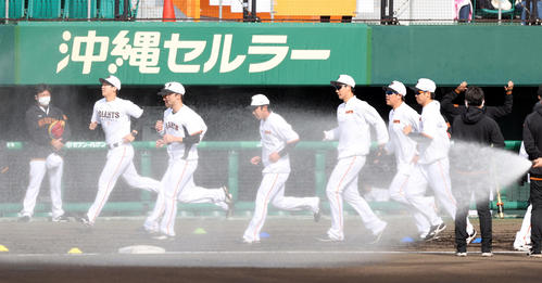 久々の晴天でグラウンドに水が巻かれる中、ウオーミングアップをする巨人の選手たち（撮影・狩俣裕三）