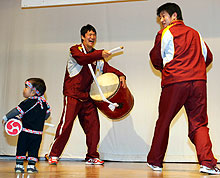 久米島町民との交流会で太鼓を抱え渡辺(右)らと踊る田中(撮影・野上伸悟)