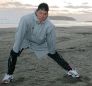 朝の散歩から戻り砂浜でストレッチする巨人大田（撮影・沢野健太）