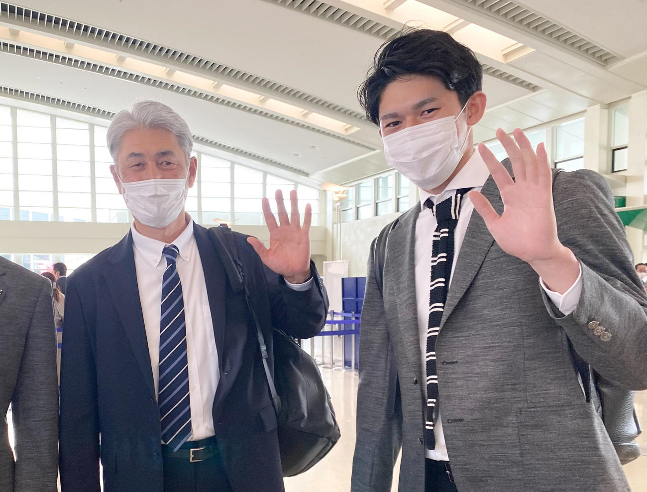 那覇空港の出発を前に笑顔で手を振るロッテの吉井監督（左）と佐々木朗（球団提供）