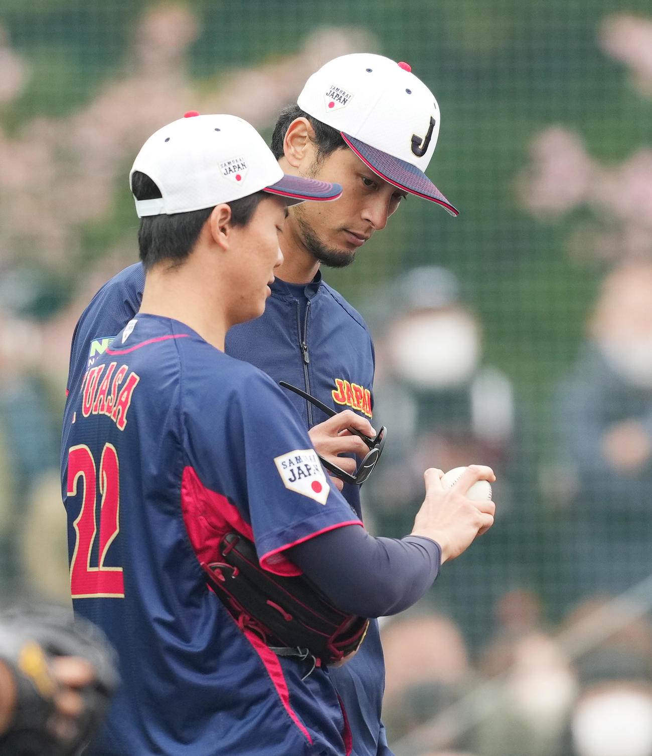 湯浅（手前）にフォークの握りを伝授するダルビッシュ（撮影・菅敏）