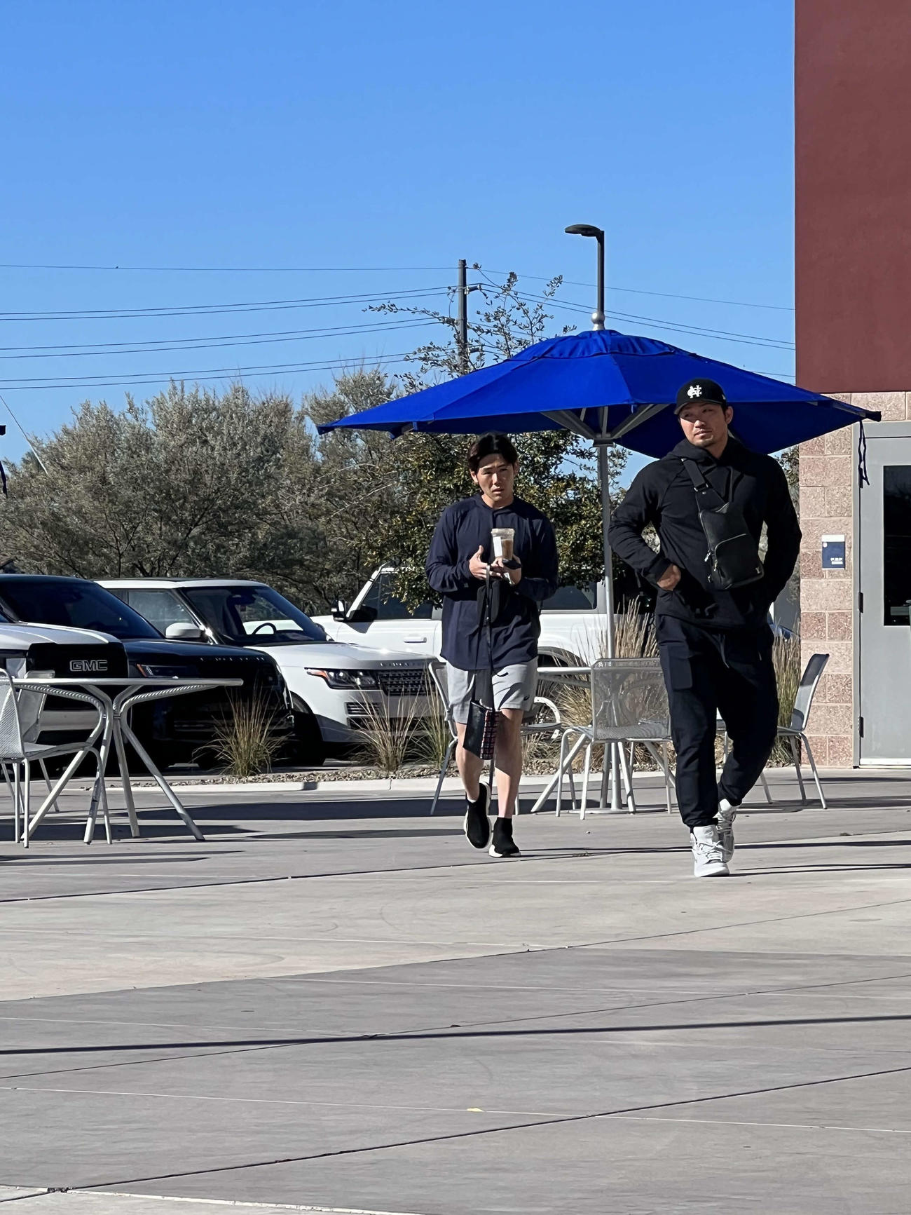 カブス鈴木（右）は、黒のスポーツウエア姿でキャンプ施設に姿を見せる。左は松下通訳