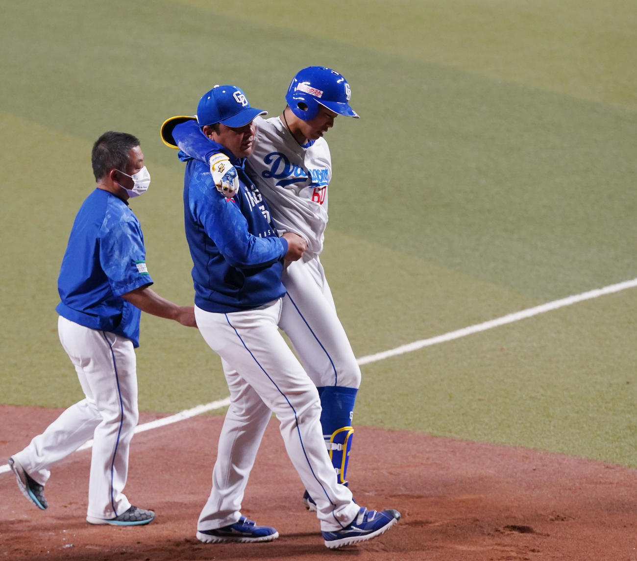 中日との合同練習でダルビッシュから右膝付近に死球を受け、森野コーチ（中央）に担がれ、負傷退場する岡林（右）（撮影・狩俣裕三）