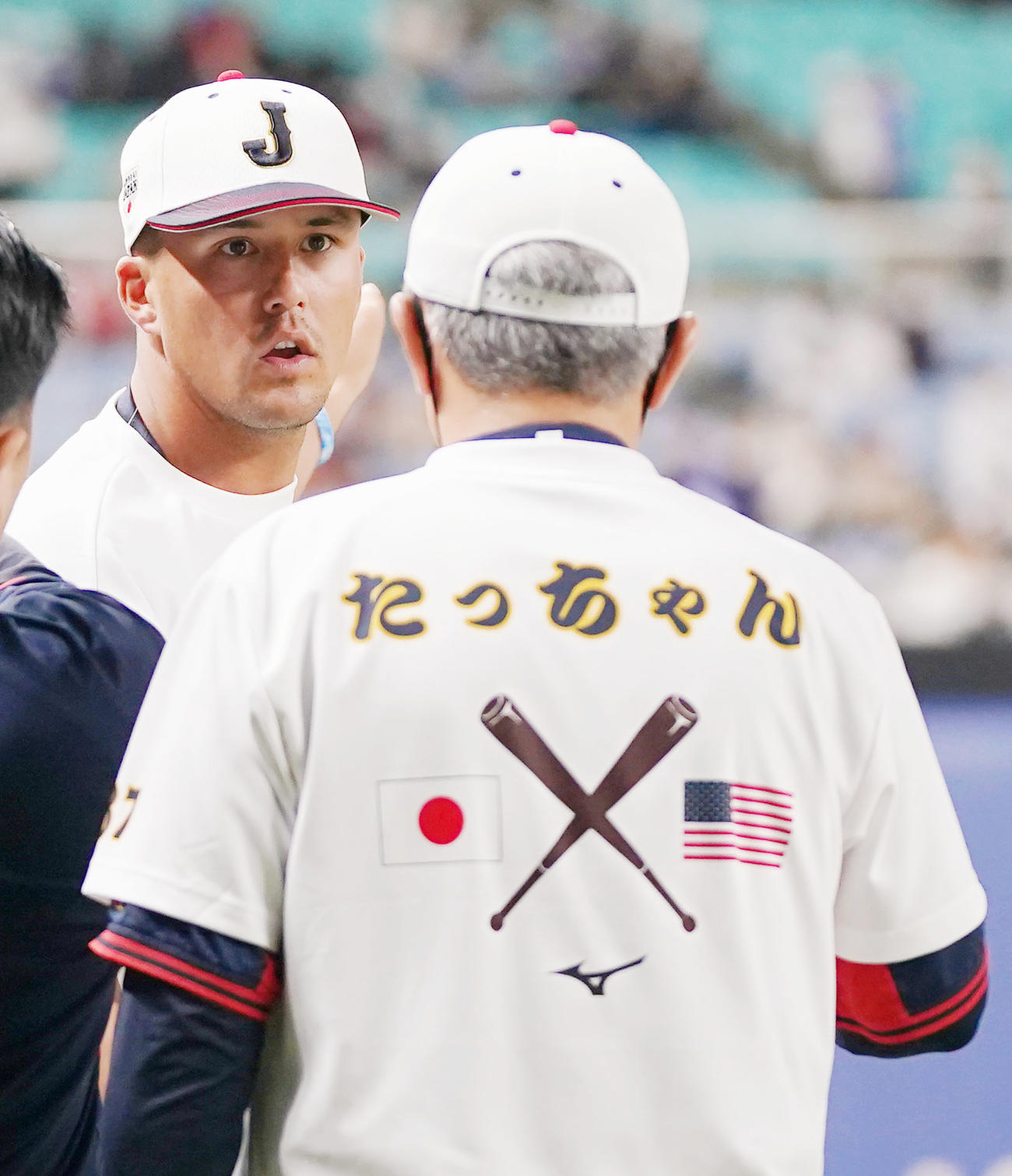 グラウンドに登場し、愛聴「たっちゃん」のTシャツを着た清水コーチ（手前）と話をするヌートバー（撮影・狩俣裕三）