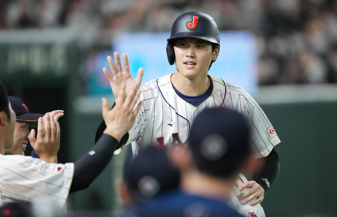 日本対中国　8回裏日本1死満塁、山田の右適時打で生還し、ナインにタッチで迎えられる大谷（撮影・菅敏）