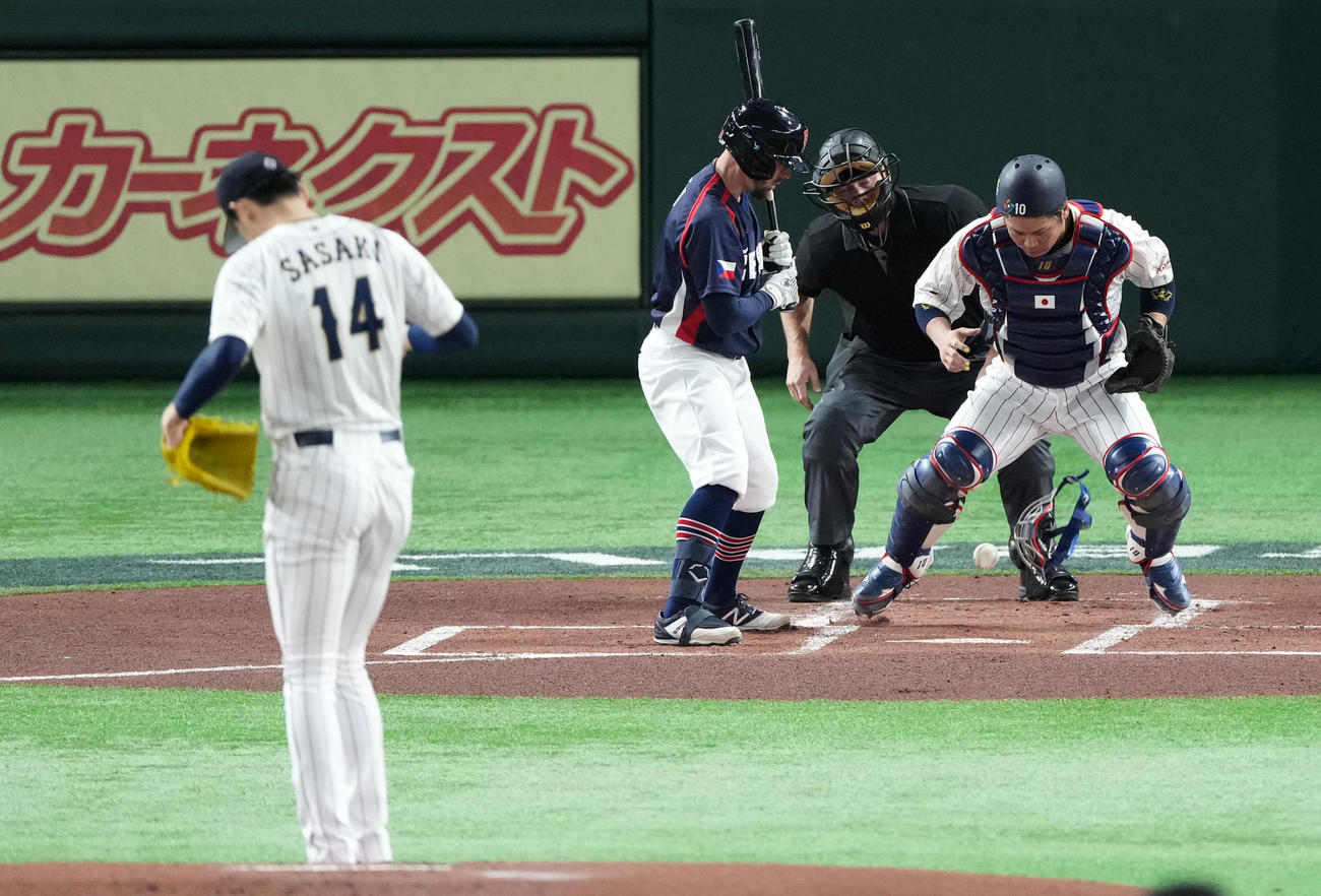 日本対チェコ　1回表チェコ1死、佐々木朗のフォークを顔面で止める甲斐（右）（撮影・横山健太）